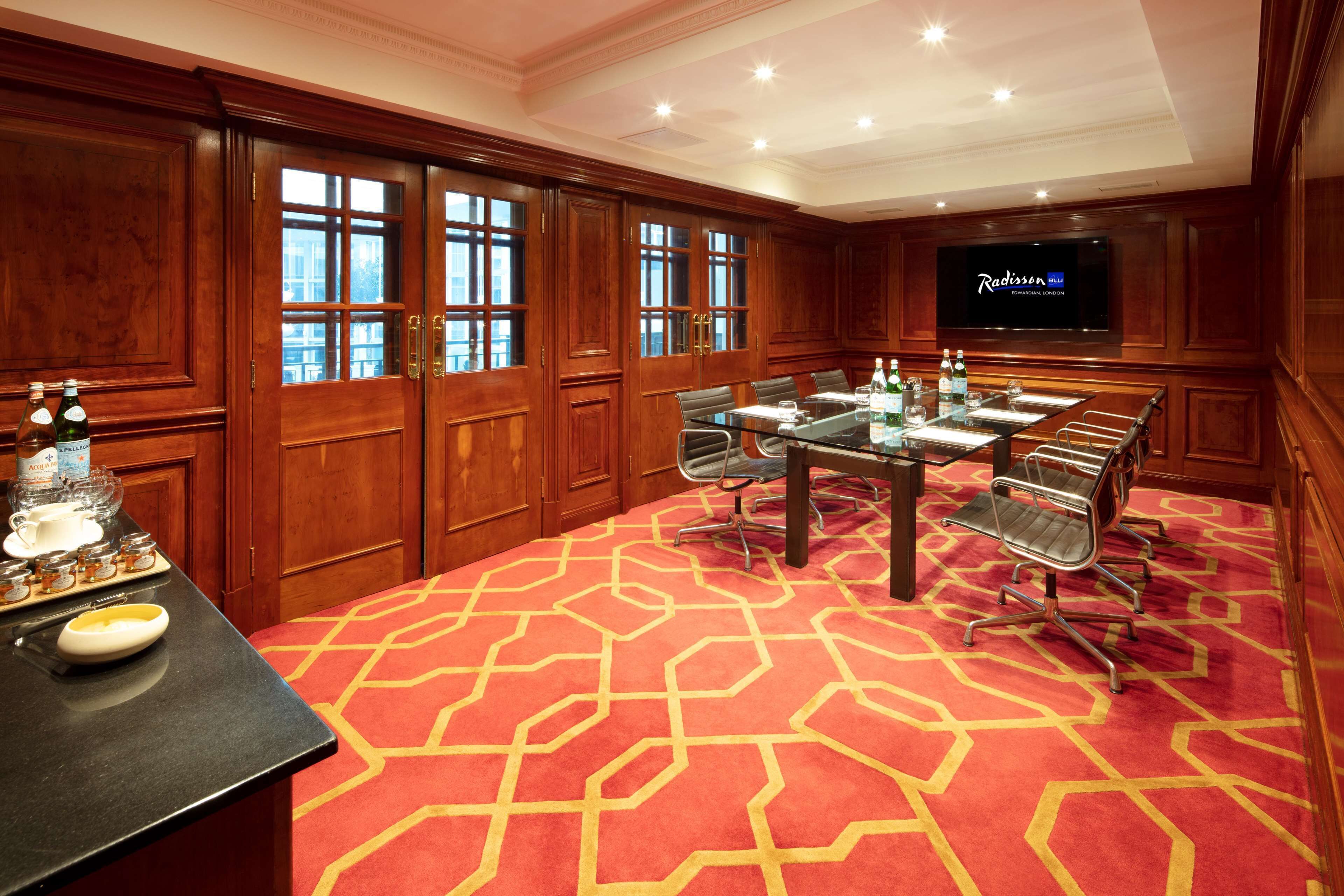A conference room with a large table, chairs, and a television screen.