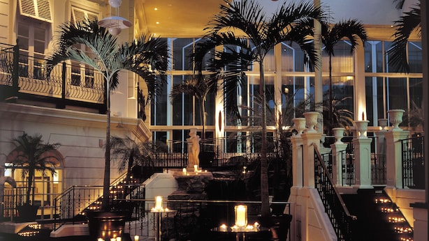 A grand lobby with a central staircase, palm trees, and a reflective floor. - Radisson Blu Hotel, London Heathrow (Hayes)