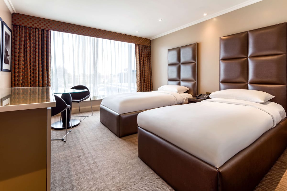 A hotel room with two beds, a desk, and a chair.
