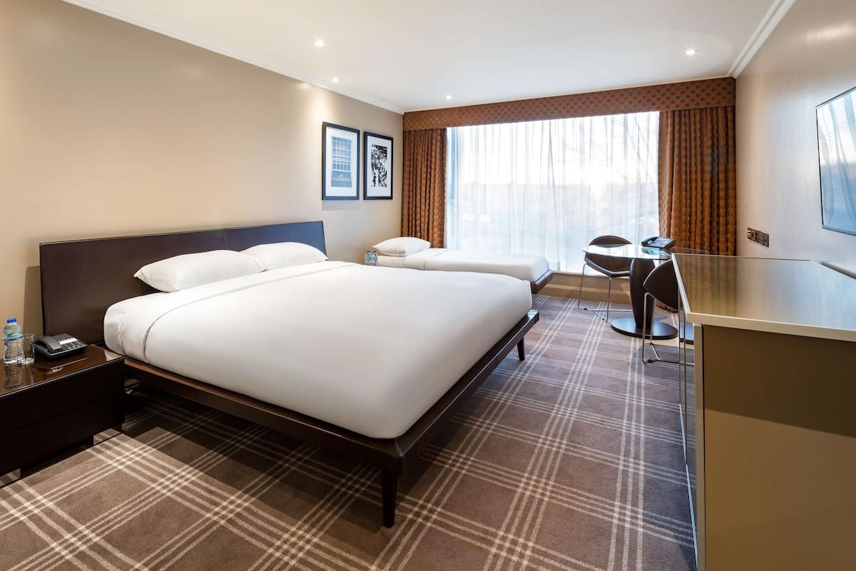 A hotel room with a large bed, a desk, and a chair.