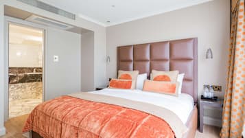 A hotel room with a large bed, a nightstand, a bathroom with a shower, and a view of the beach.
