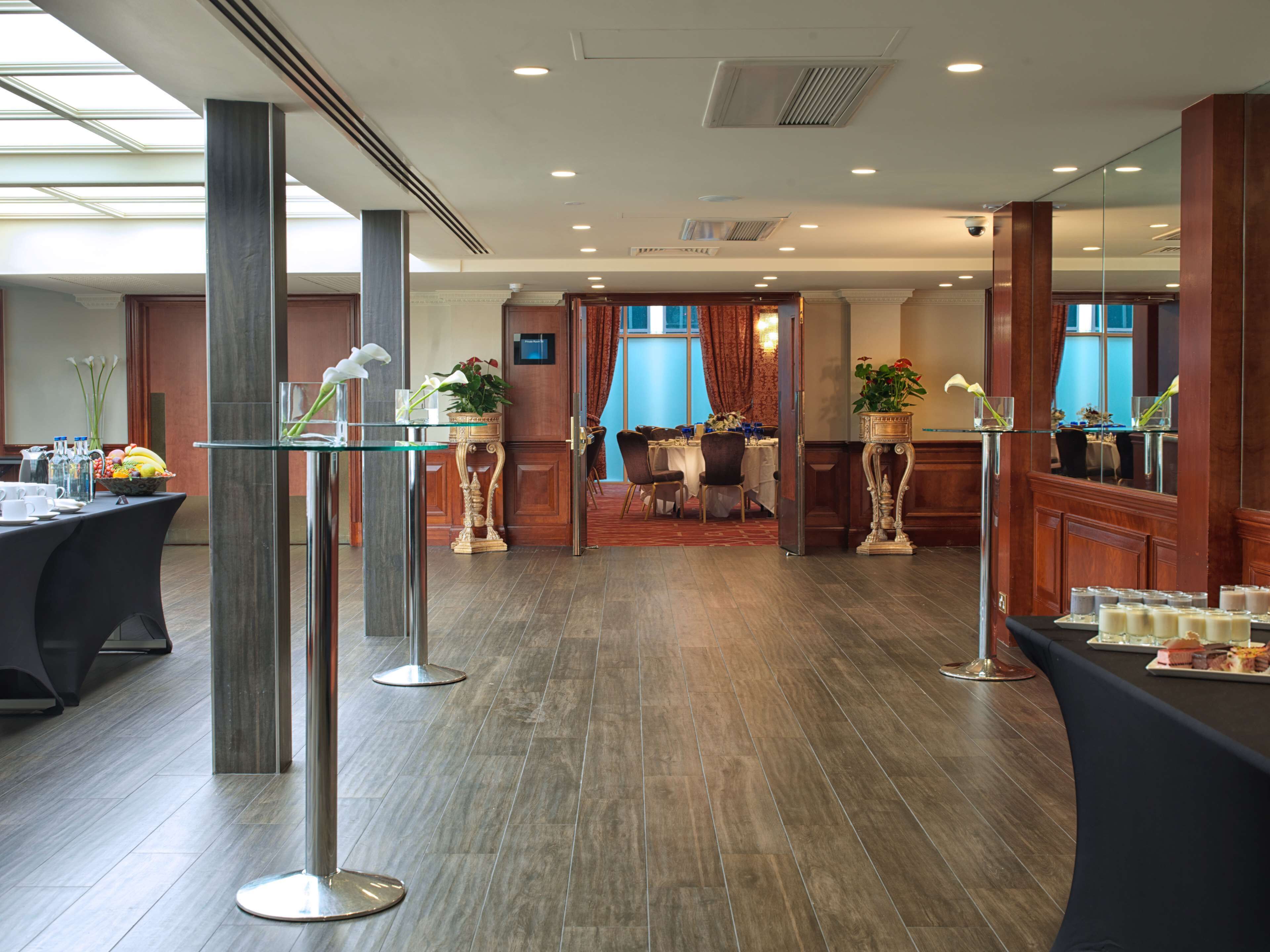 A spacious hotel lobby with a reception desk, a dining area, and a conference room.