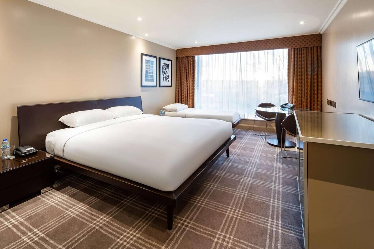 A hotel room with a large bed, a desk, and a chair.