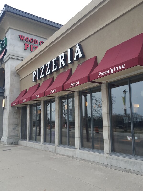 A pizzeria with a large sign reading "PIZZERIA" and menu items listed below.