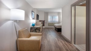 A hotel room with a bed, a desk, a chair, a lamp, and a window. - Quality Inn & Suites (Niagara Falls)