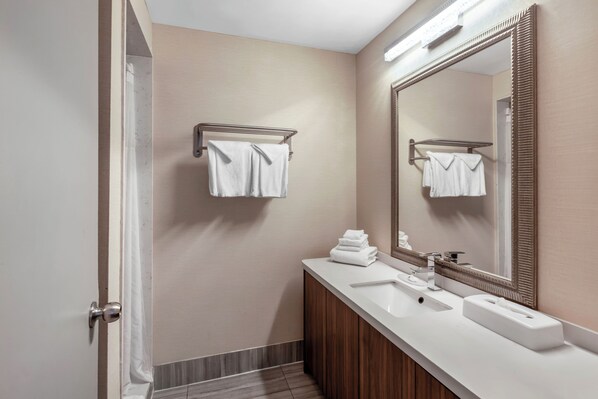 A modern bathroom with a white sink, a large mirror, and a towel rack.
