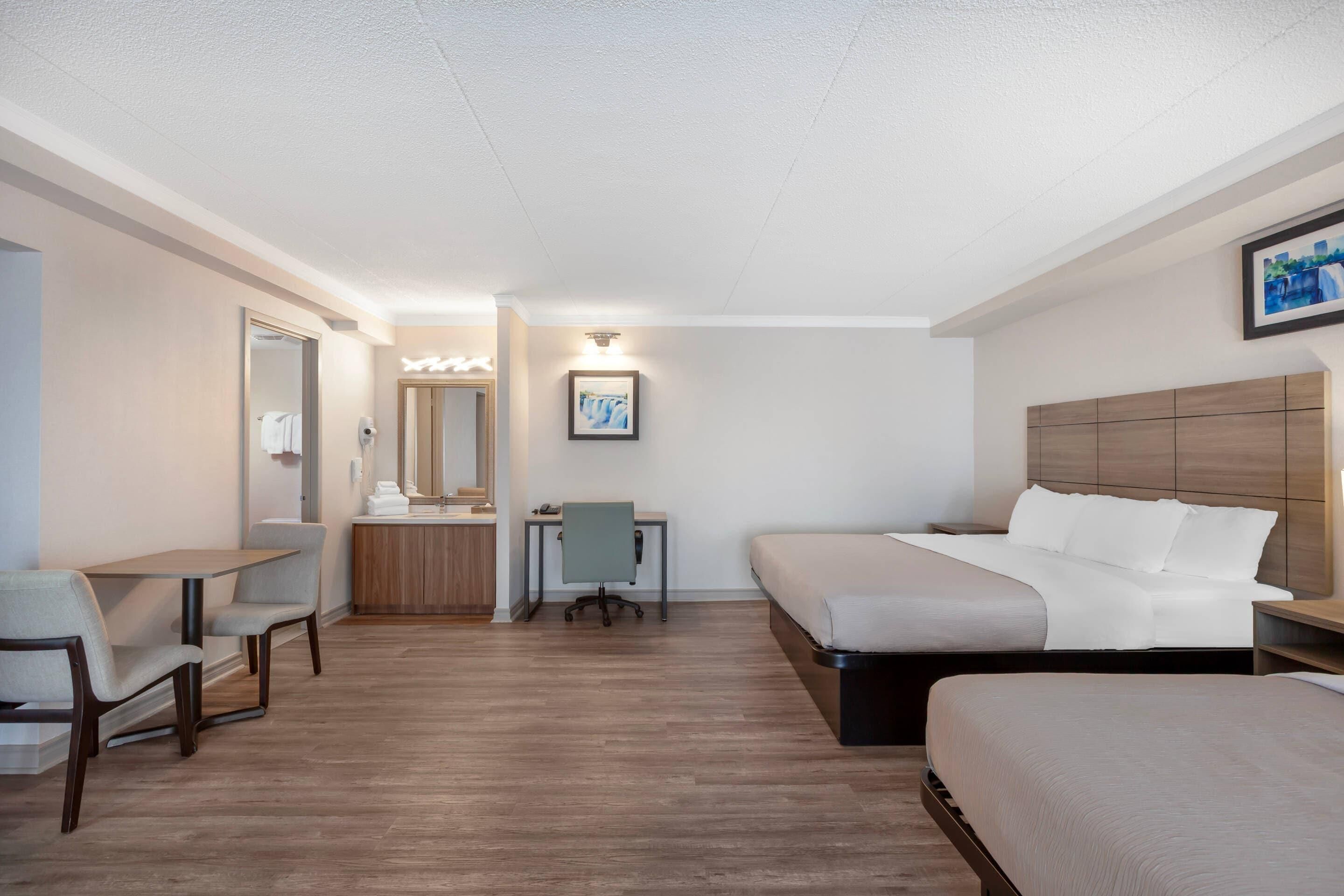 Una habitación de hotel con una cama, un escritorio, una silla, una mesita y un espejo.