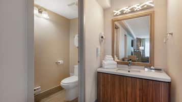 A modern bathroom with a toilet, vanity, and a large mirror.