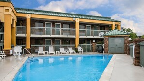 A multi-story hotel with a swimming pool, outdoor seating, and a brick facade. - Quality Inn Franklin South (Franklin)