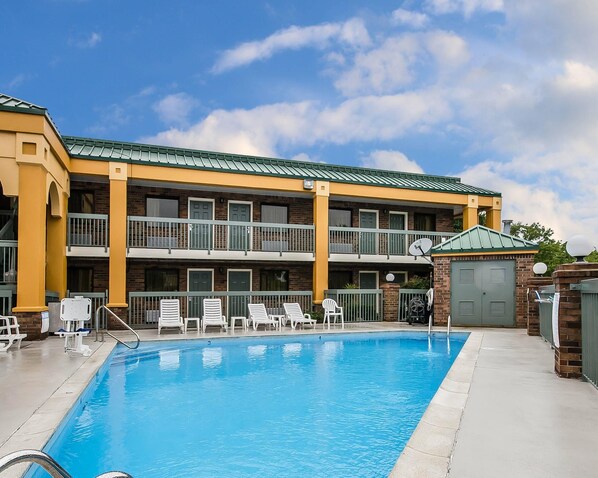 A multi-story hotel with a swimming pool, outdoor seating, and a brick facade.