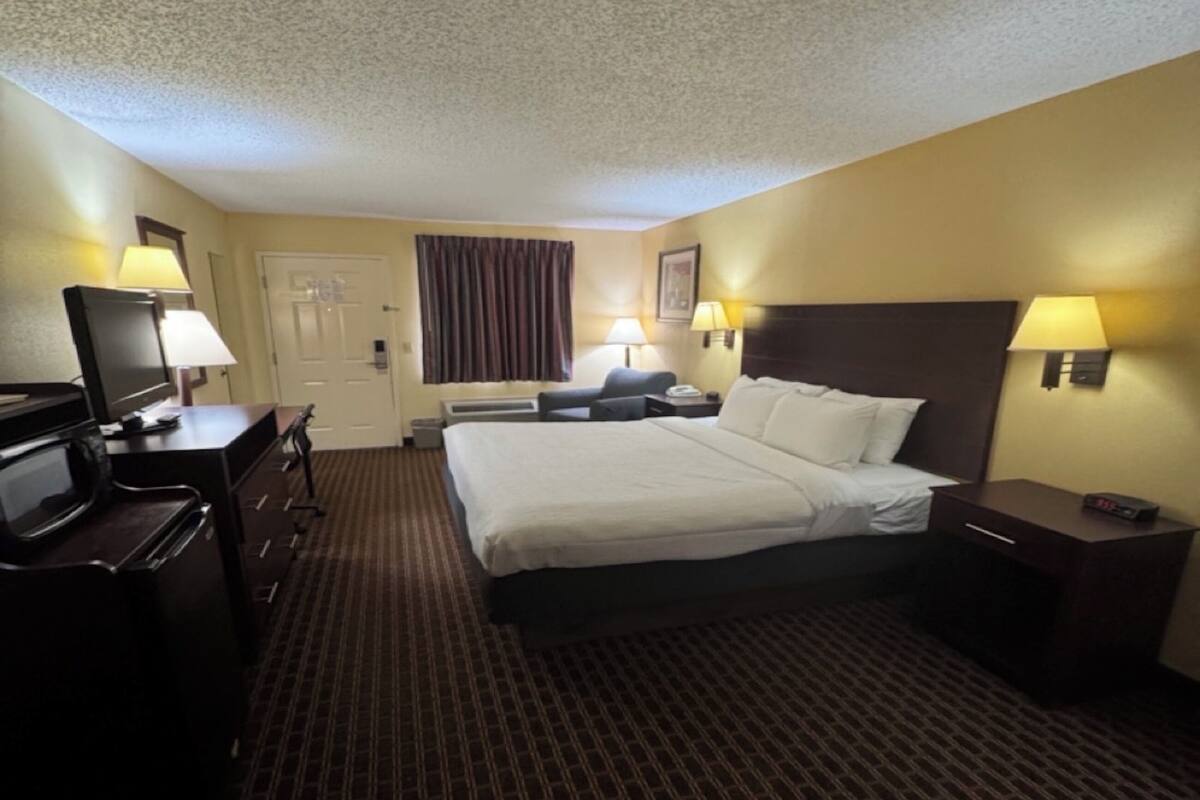 A hotel room with a bed, desk, TV, and lamps.