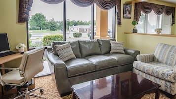 A living room with a leather sofa, patterned armchair, and a glass coffee table.