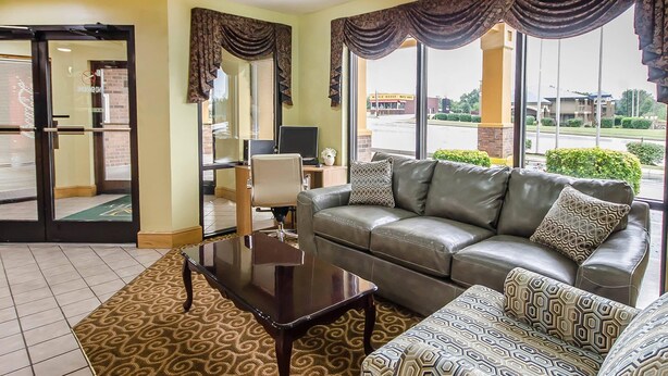A hotel lobby with a sofa, a coffee table, patterned rugs, and large windows with curtains. - Quality Inn Franklin South (Franklin)