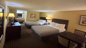 A hotel room with two beds, a desk with a chair, a lamp, and a small table. - Quality Inn Franklin South (Franklin)