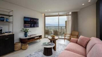 Una sala de estar moderna con un sofá, una mesa de centro, un televisor y un balcón con vistas.