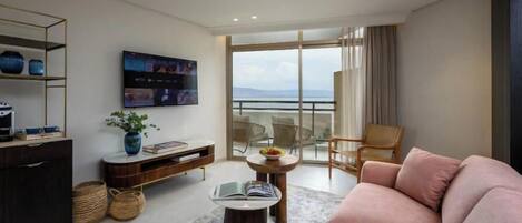 Una sala de estar moderna con un sofá, una mesa de centro, un televisor y un balcón con vistas.