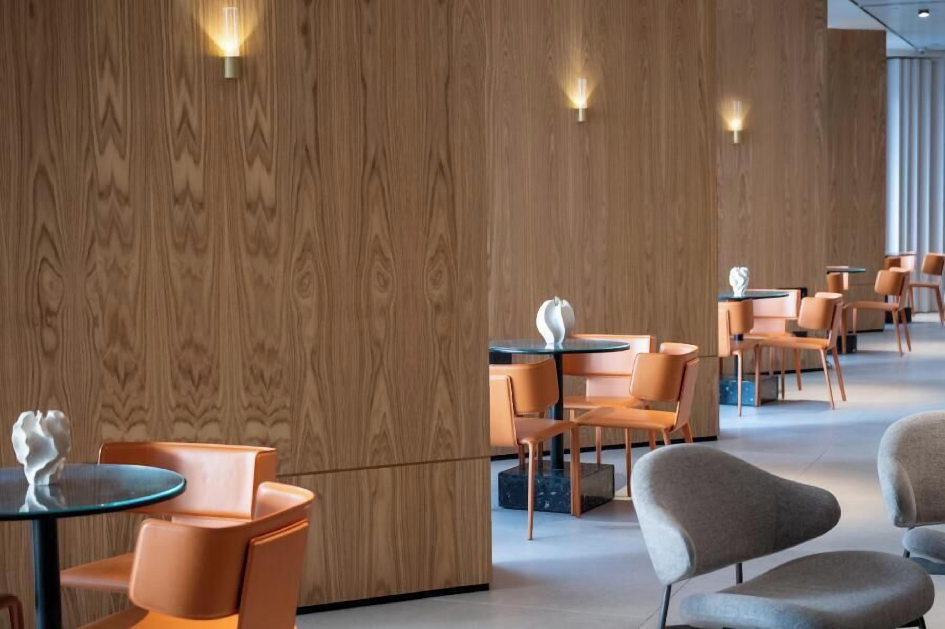 A modern interior with wooden panel walls, round tables, and contemporary chairs.