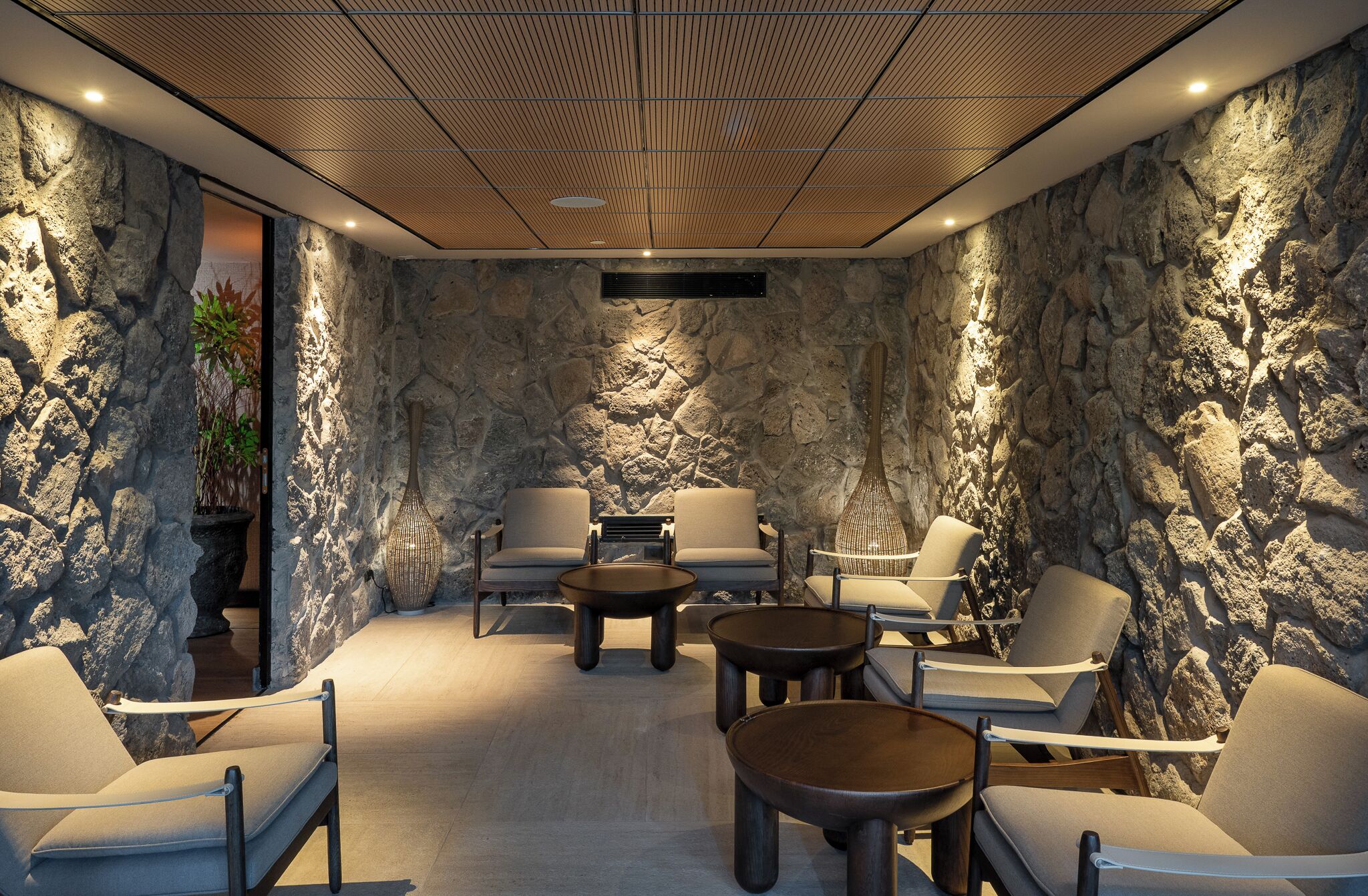 A modern lounge with stone walls, comfortable seating, and a wooden ceiling.