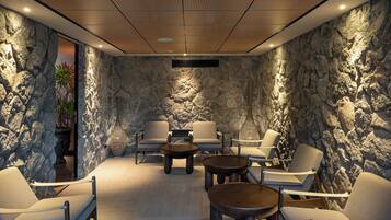 A modern lounge with stone walls, comfortable seating, and a wooden ceiling.