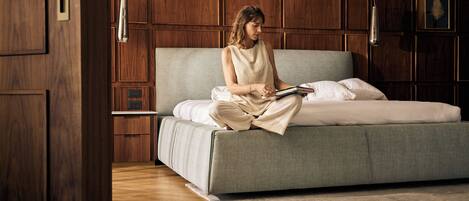 A room with a large bed, wooden panel walls, a bedside table, and a nightstand.