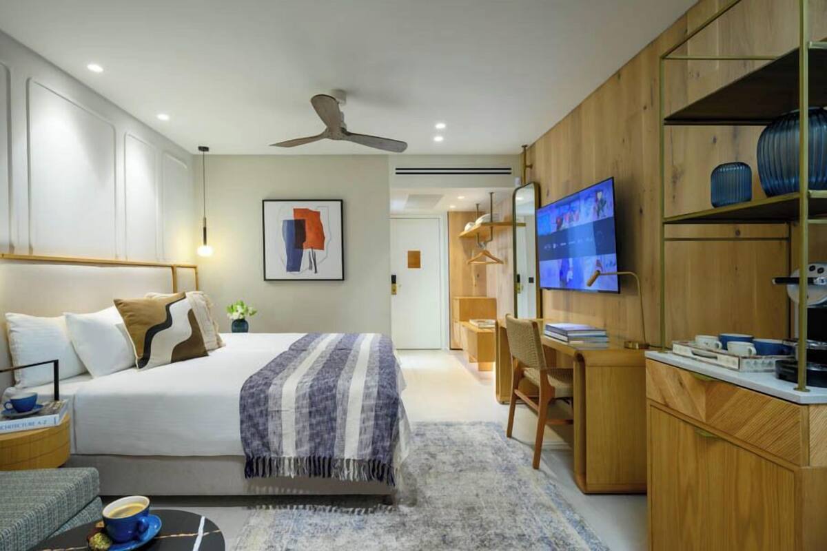 A modern bedroom with a bed, a desk, a television, and a wardrobe.