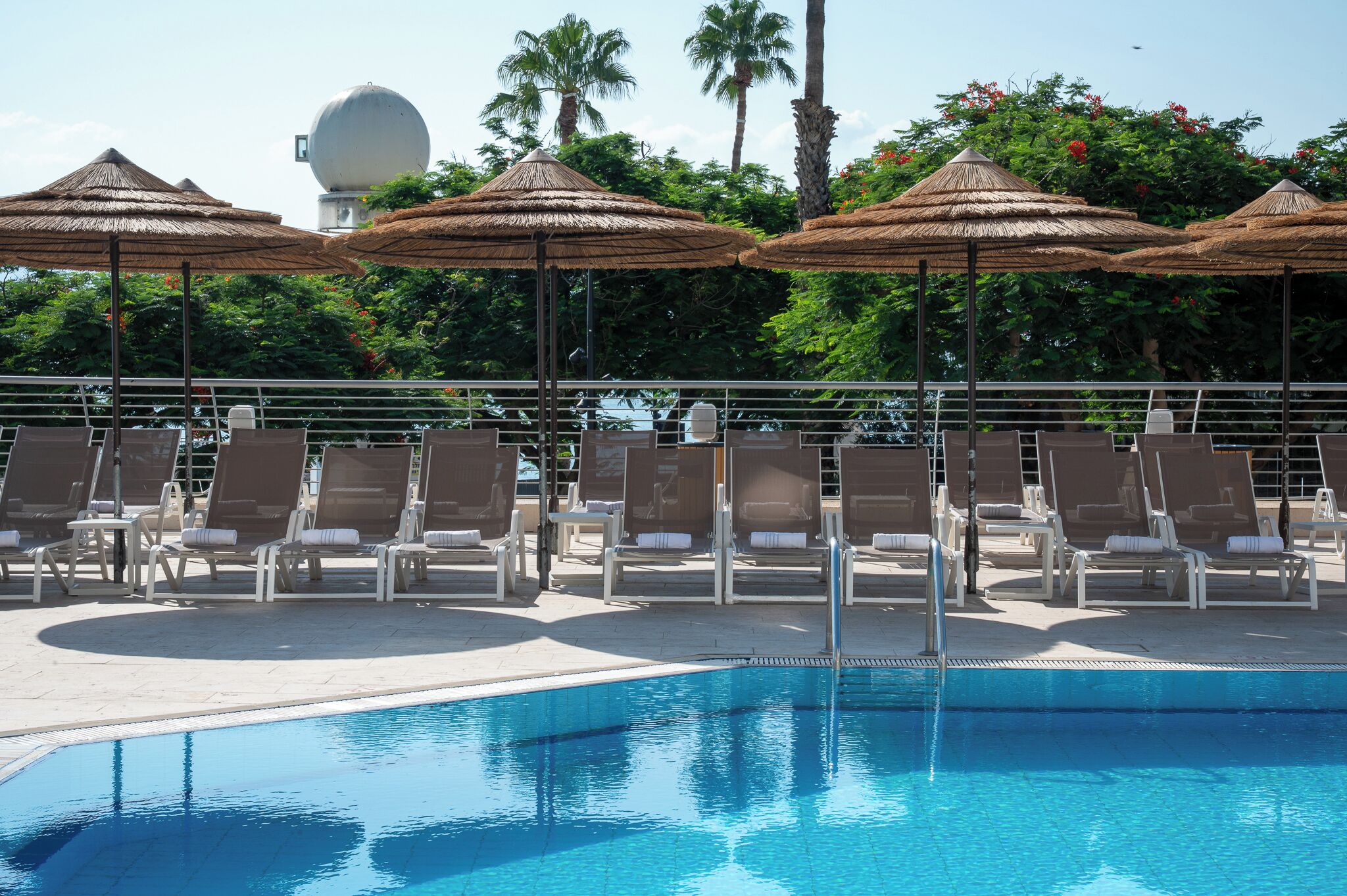 Un espace aménagé au bord de la piscine, avec des chaises longues et des parasols.