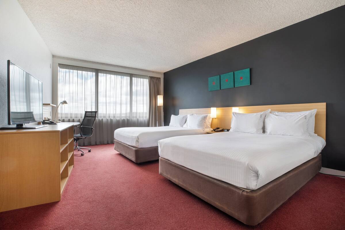 Een hotelkamer met twee bedden, een bureau, een stoel en een televisie.
