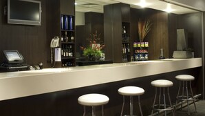 A bar area with a counter, stools, a phone, and shelves with bottles.