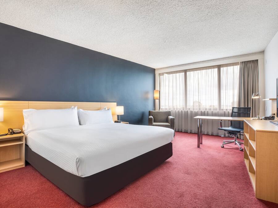 Una camera d'hotel con un letto grande, una scrivania, una sedia e una finestra con tende.