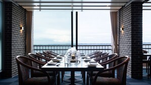 Un comedor con una mesa larga, sillas y vista al mar.