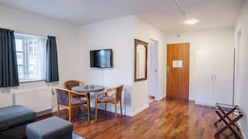 Una habitació moderna amb terra de fusta, una taula de dinar amb cadires, un televisor i un armari.