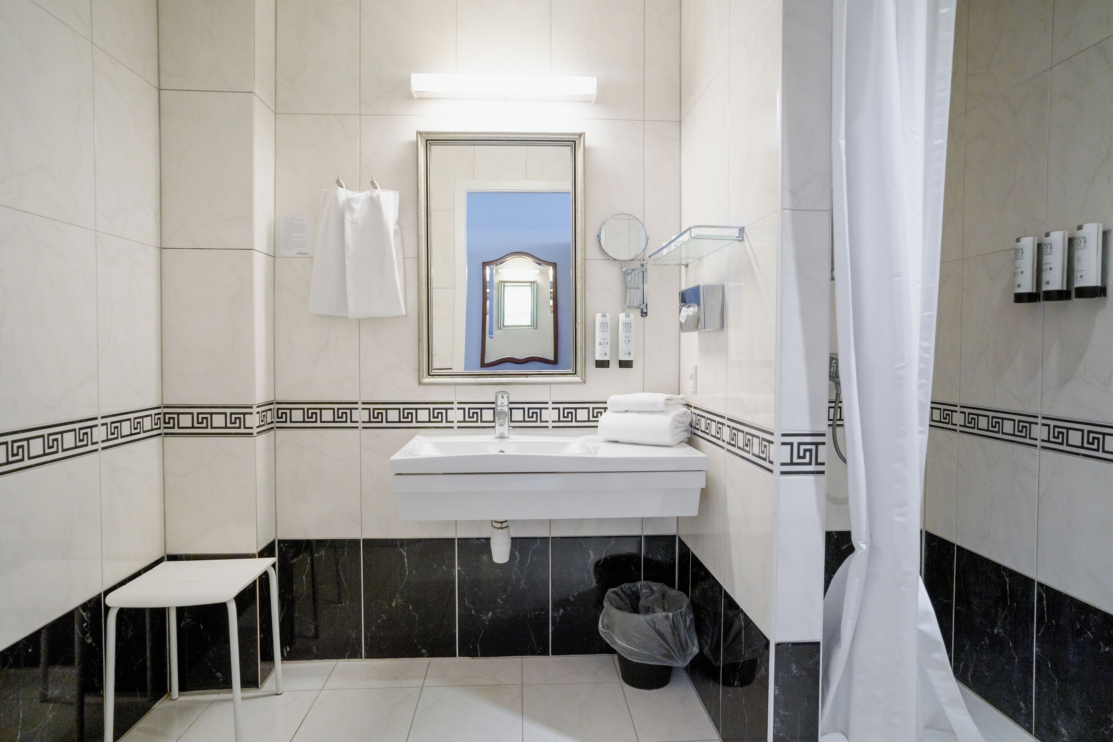 A bathroom with a white sink, mirror, and black marble tiles.