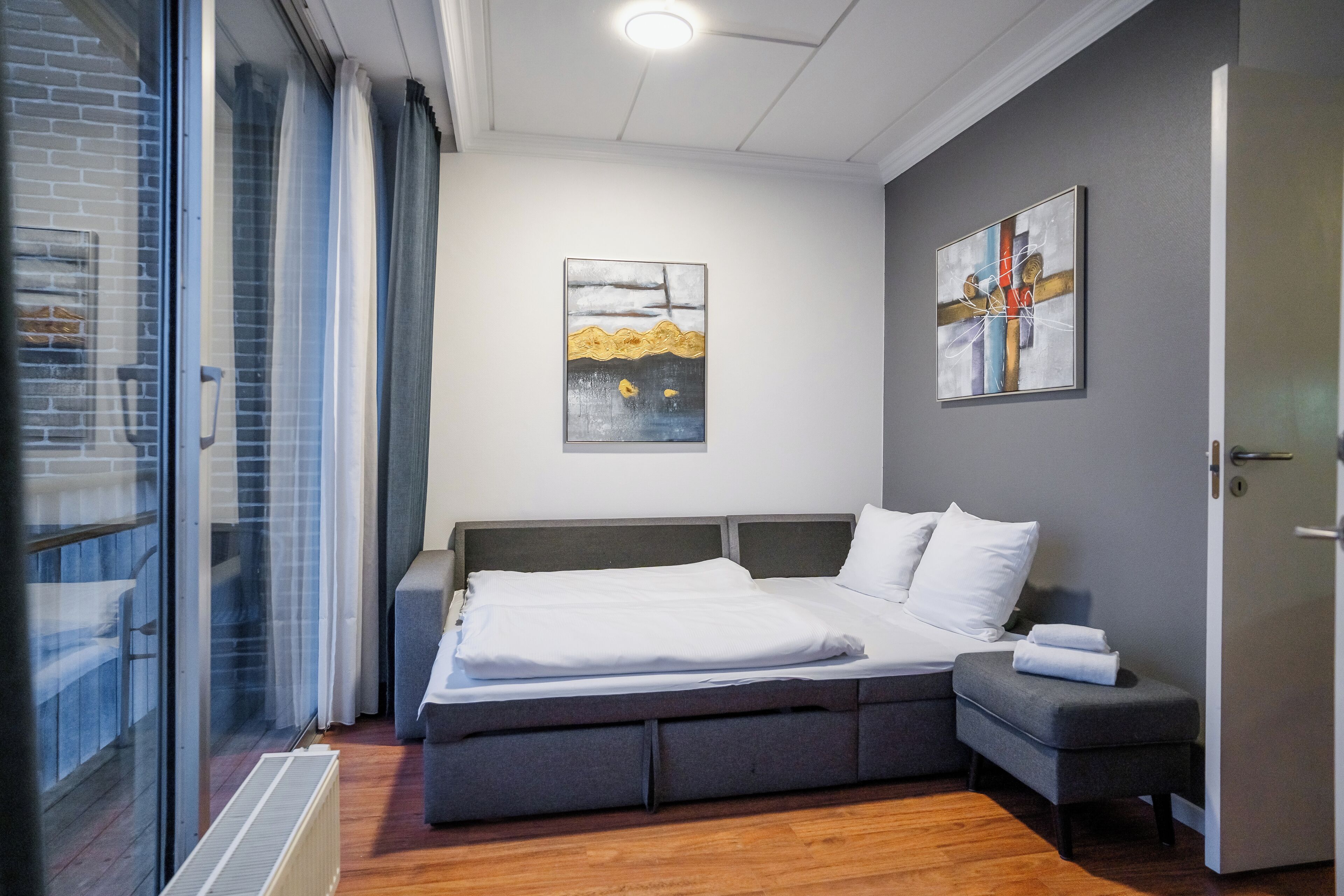 A modern bedroom with a bed, bedside tables, and a grey bench.