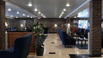 Un vestíbulo con mostrador de recepción, zona de estar y una planta en maceta.