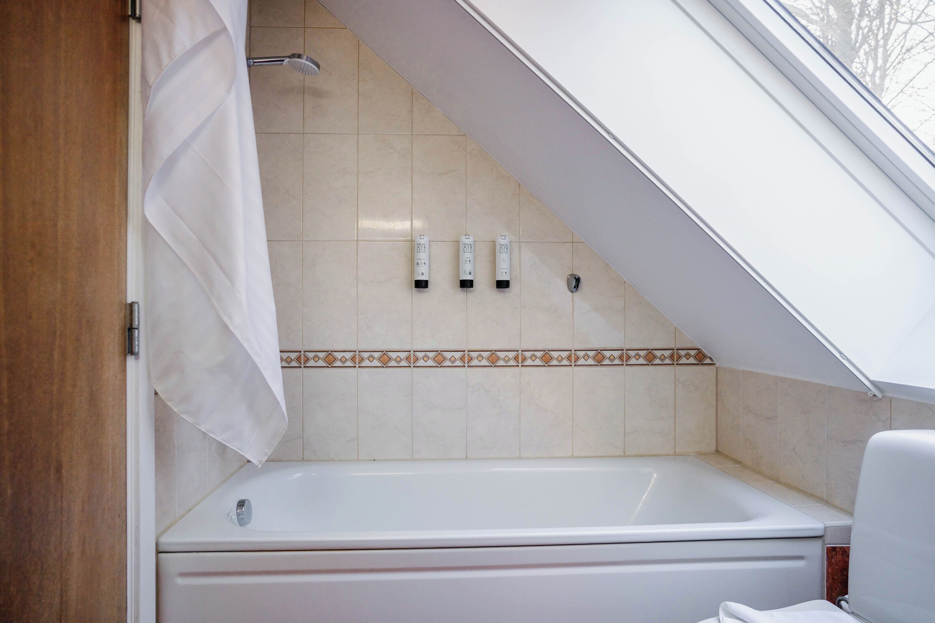 A bathroom with a bathtub, a shower, and a window.