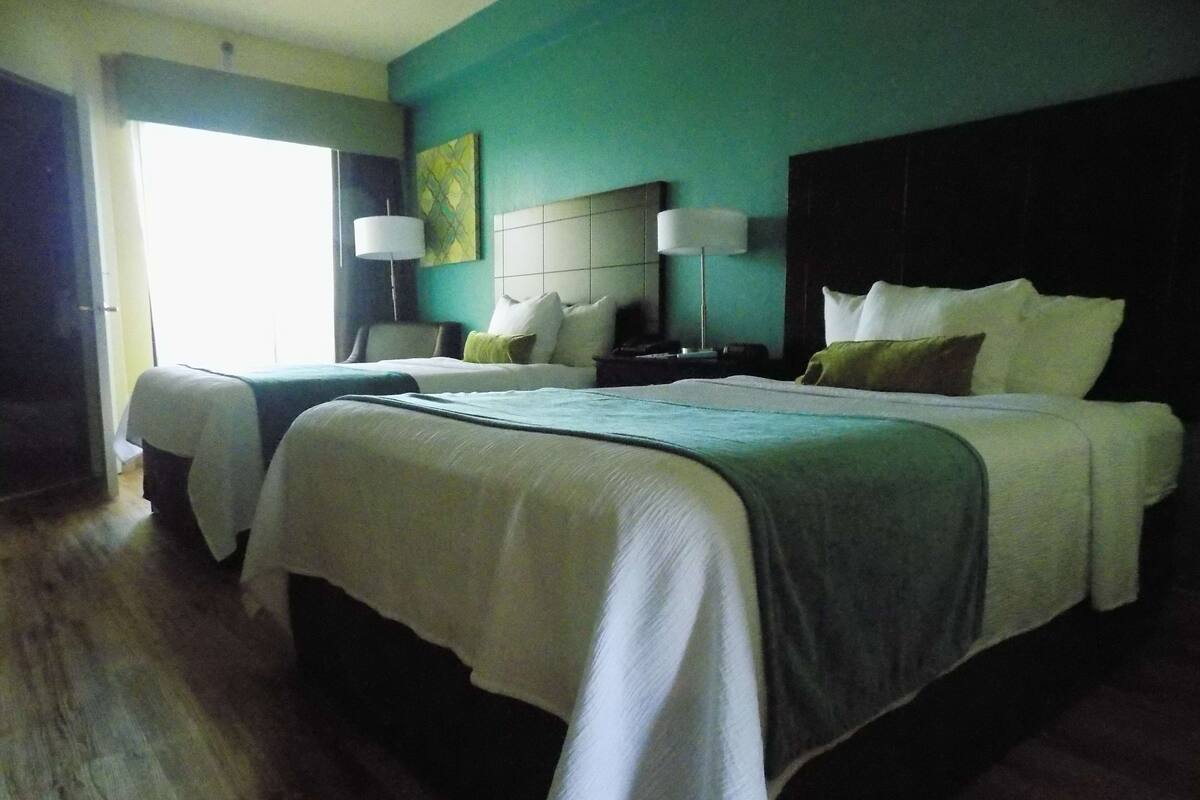 Una habitación de hotel con dos camas, un ventanal grande y un cuadro en la pared.