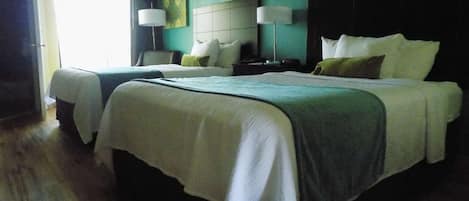 Una habitación de hotel con dos camas, un ventanal grande y un cuadro en la pared.
