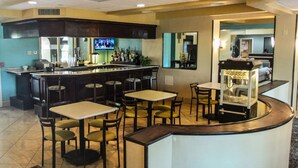 A bar area with multiple seating options, a television, and a counter with various bottles.