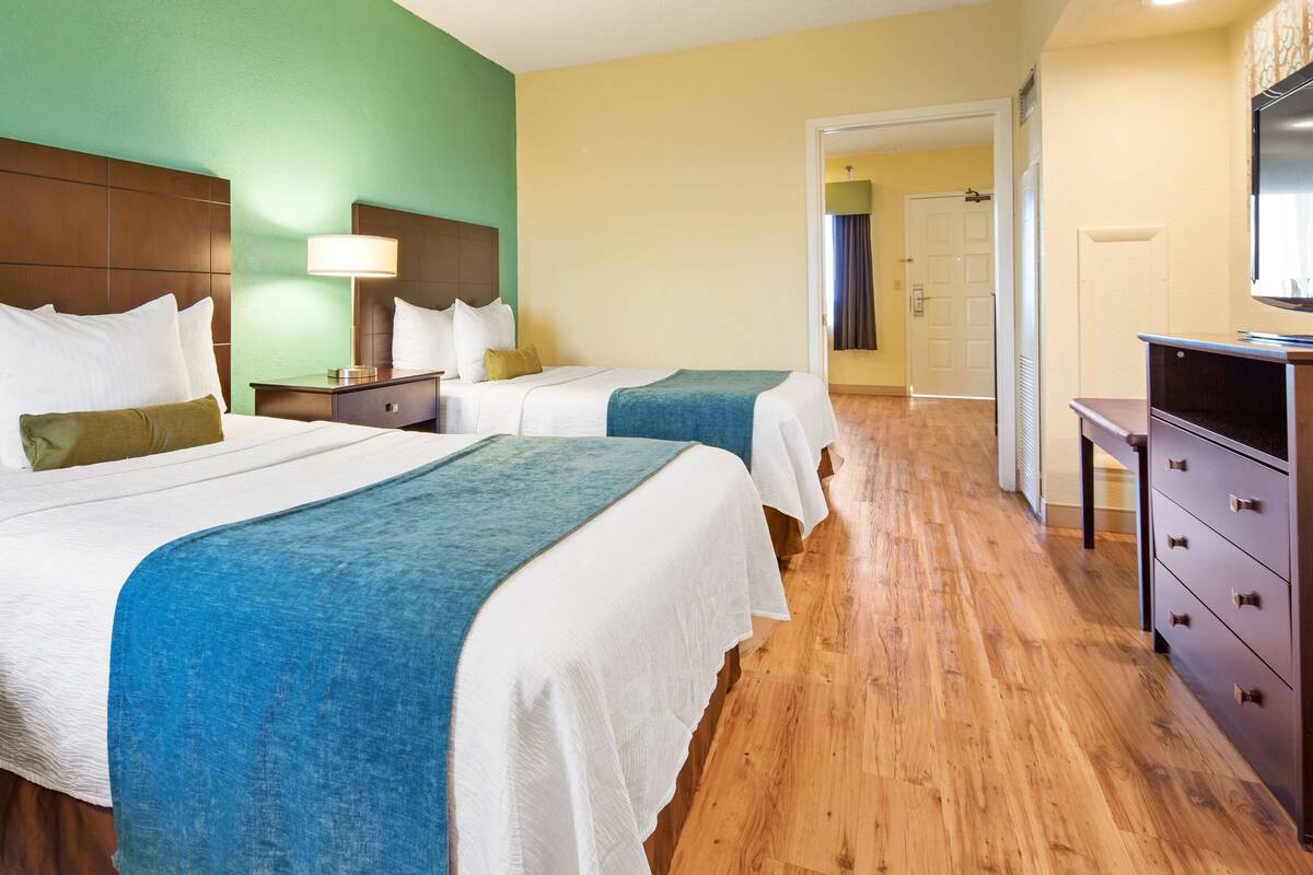 Una habitación de hotel con dos camas, un escritorio y un aparador.