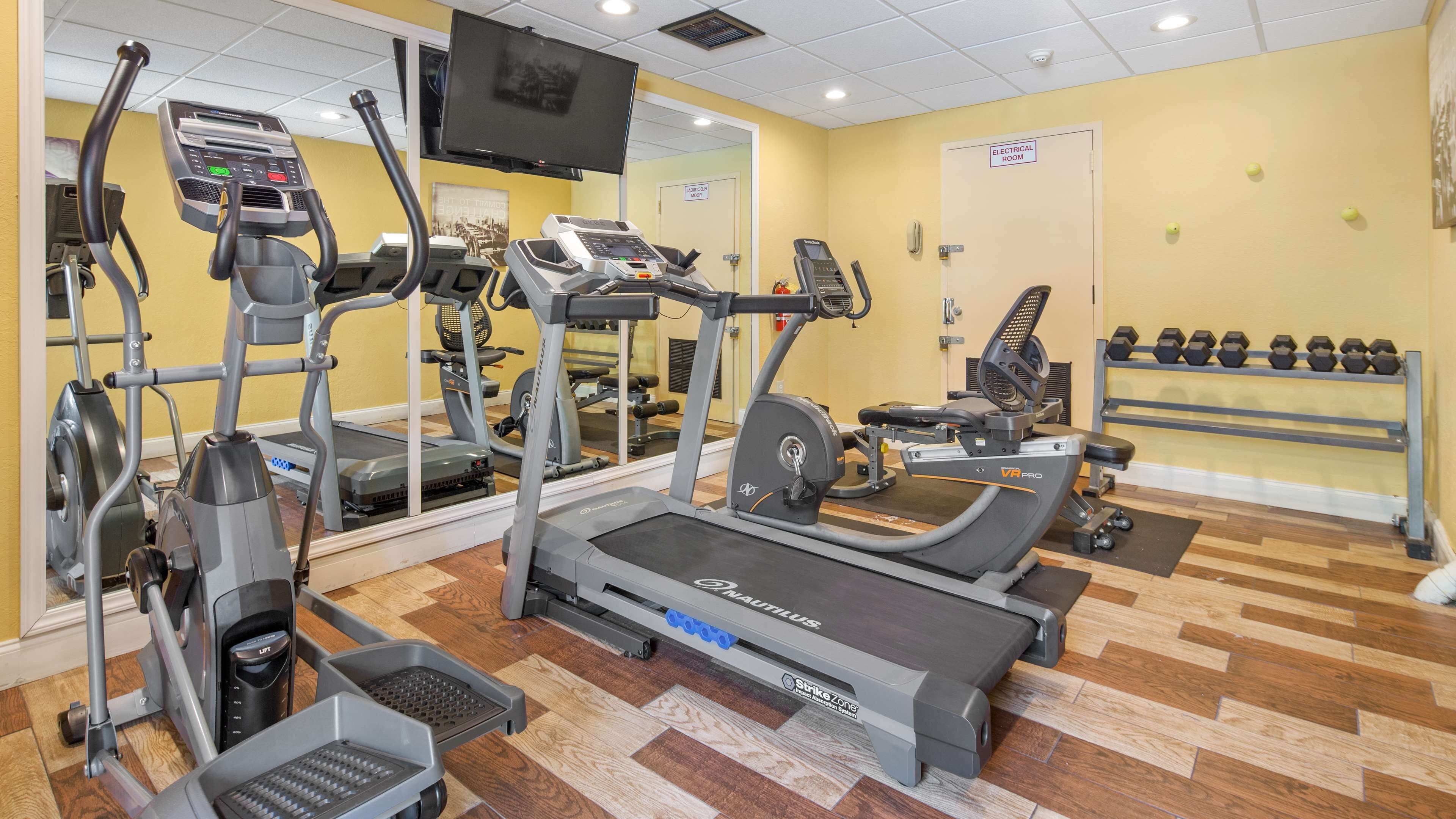 Een fitnessruimte met loopbanden, elliptische trainers en een roeimachine.