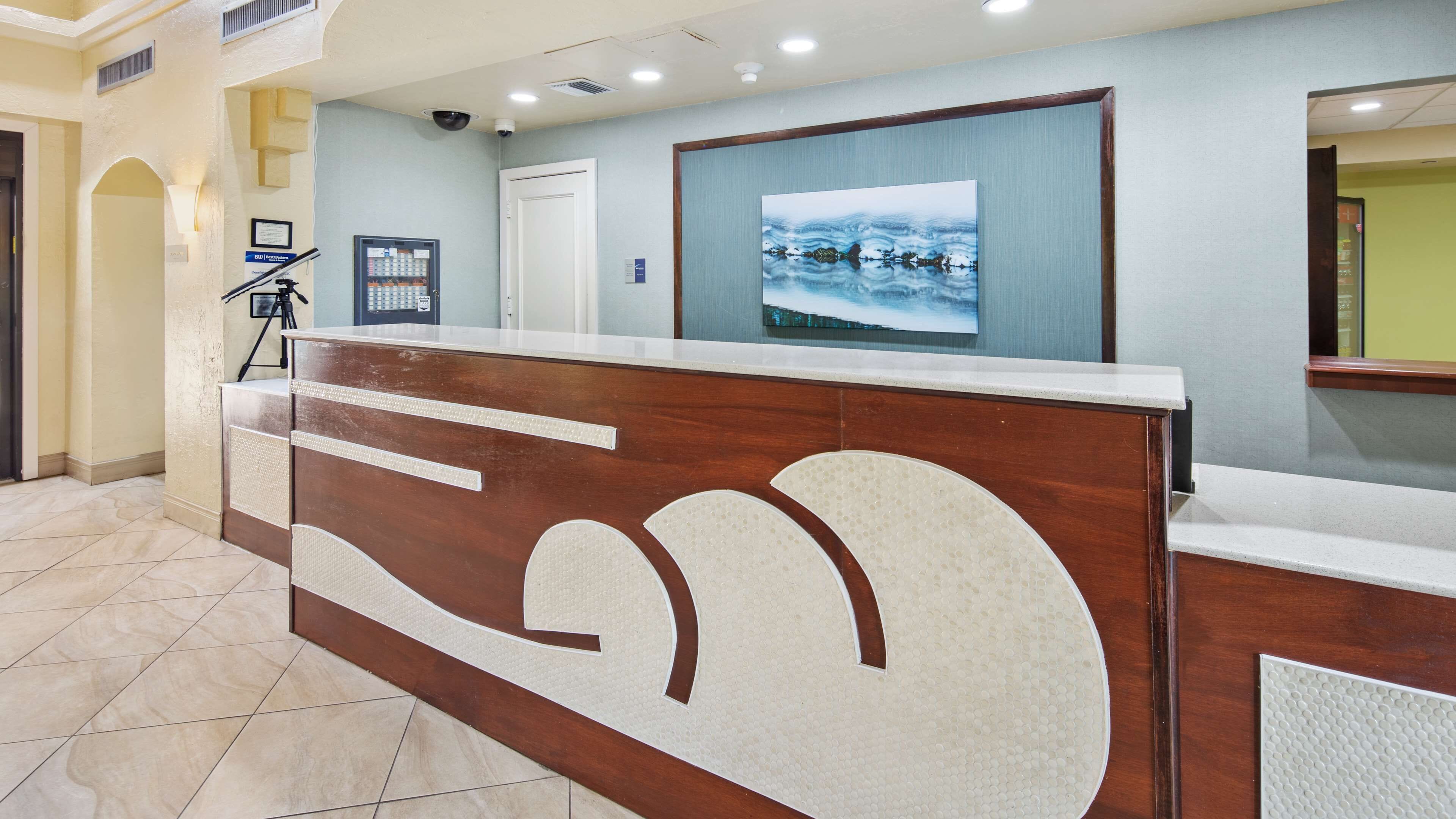 A reception desk with a modern design, a security camera, and a framed artwork above it.
