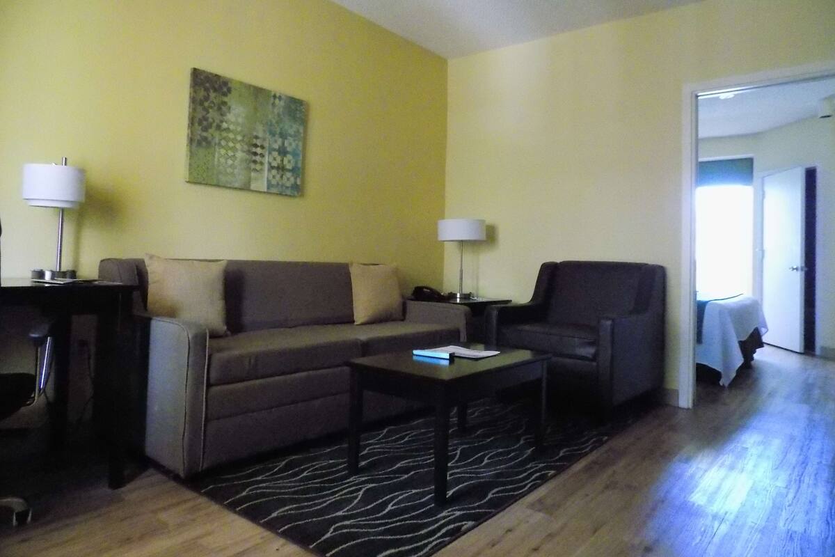 Una sala de estar con sofá, sillón, mesa de centro y lámparas.