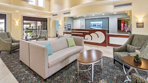 A lobby with a reception desk, seating area, and a Coca-Cola refrigerator.