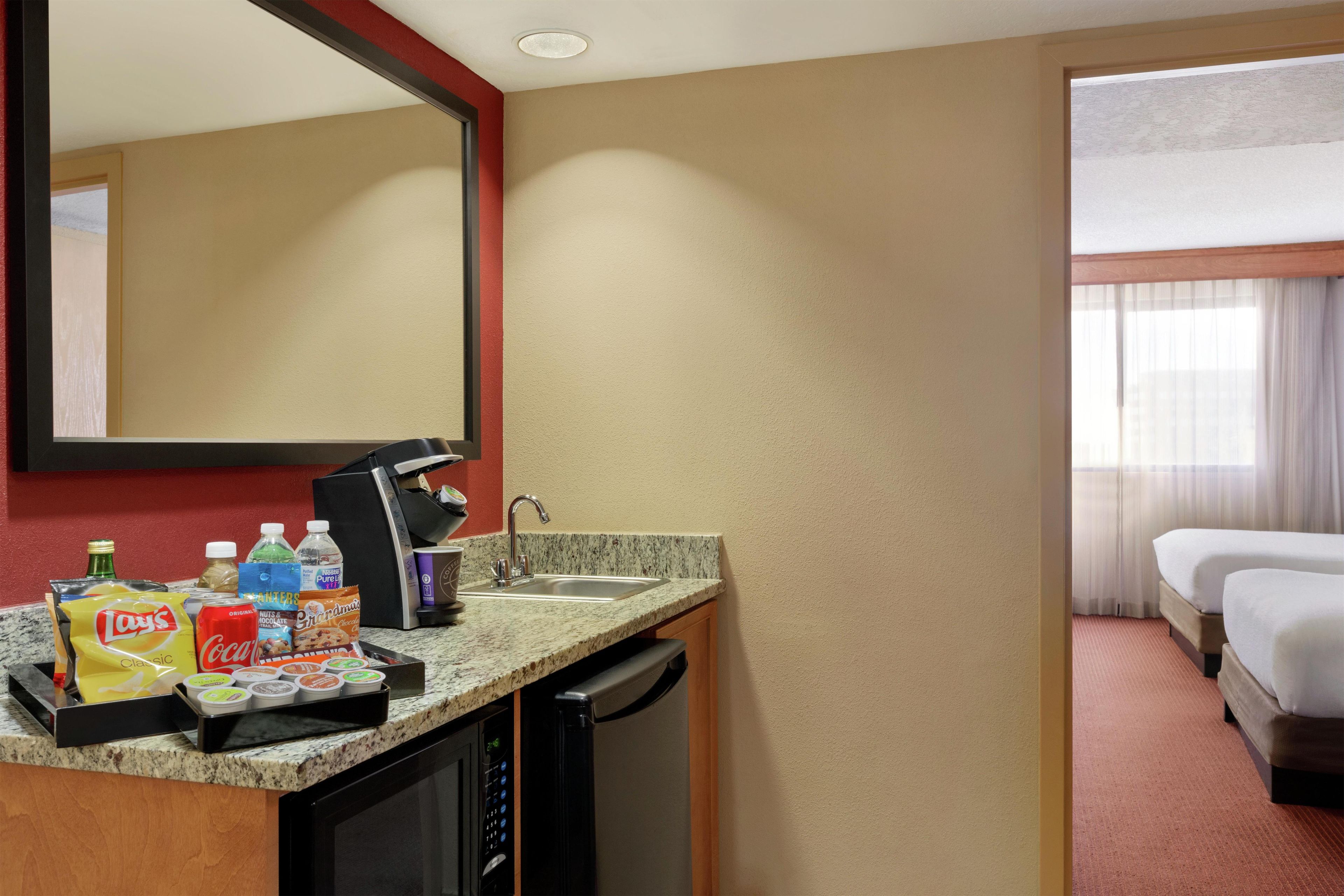 Una habitación de hotel con kitchenette, una cama y baño.