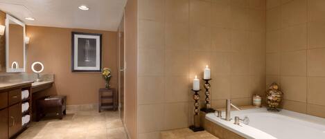 A modern bathroom with a large bathtub, a vanity with a mirror, and a framed picture on the wall.
