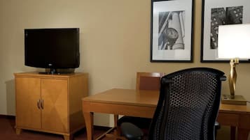 Ett hotellrum med ett träskåp, en tv, ett skrivbord, en stol och två inramade tavlor på väggen.