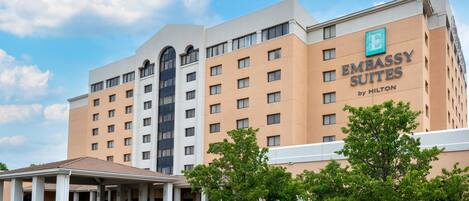 A multi-story hotel building with a prominent sign for 'Embassy Suites by Hilton' on the facade.