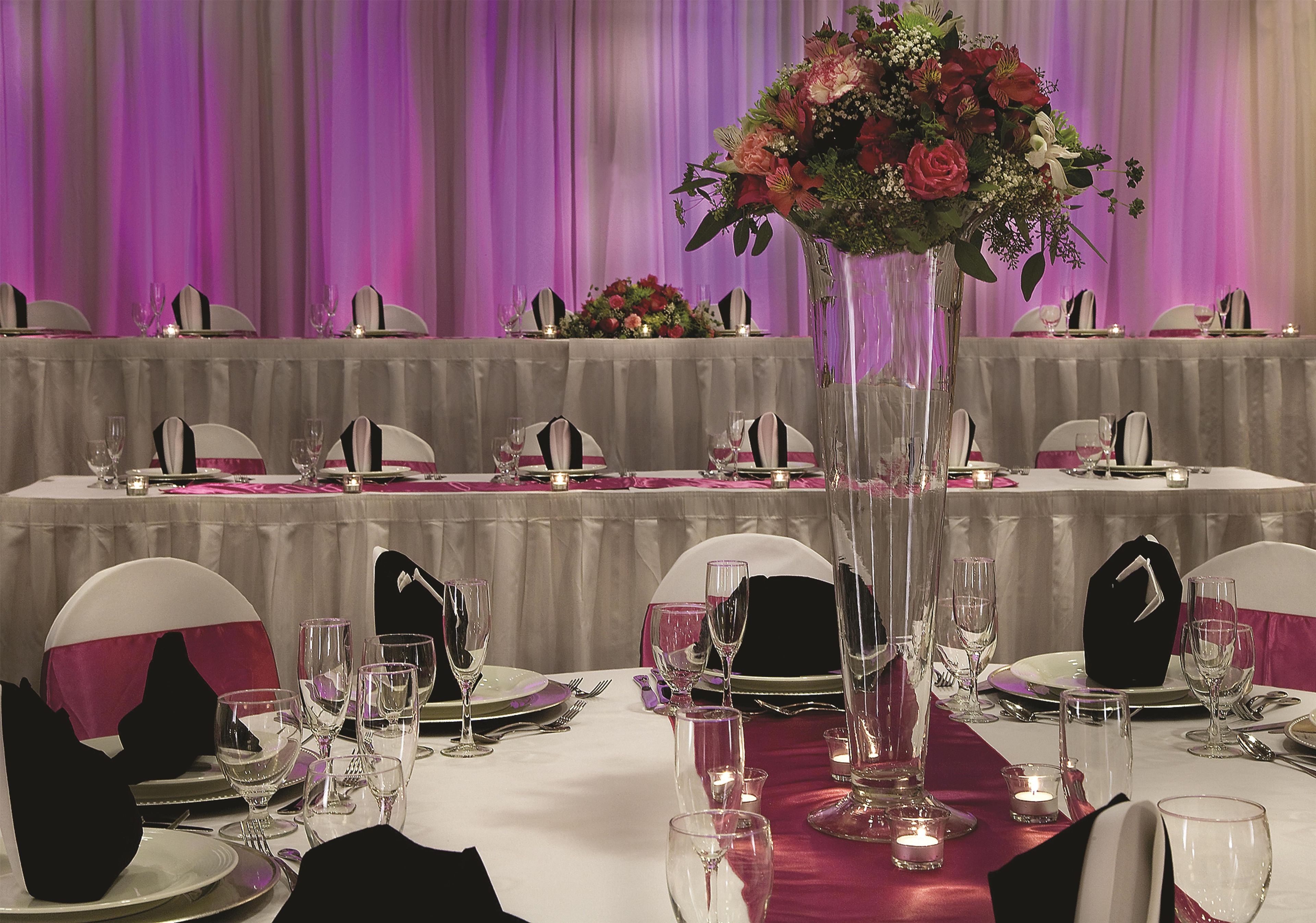 A banquet table set for a formal event with multiple place settings, glasses, and a centerpiece.