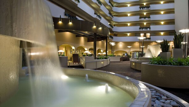 A multi-level atrium with a central water feature, seating areas, and indoor plants. - Embassy Suites by Hilton Kansas City International Airport (Kansas City)
