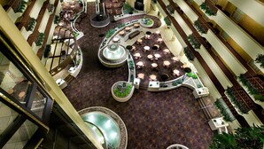 A spacious atrium with multiple levels, featuring a central fountain, seating areas, and potted plants. - Embassy Suites by Hilton Kansas City International Airport (Kansas City)